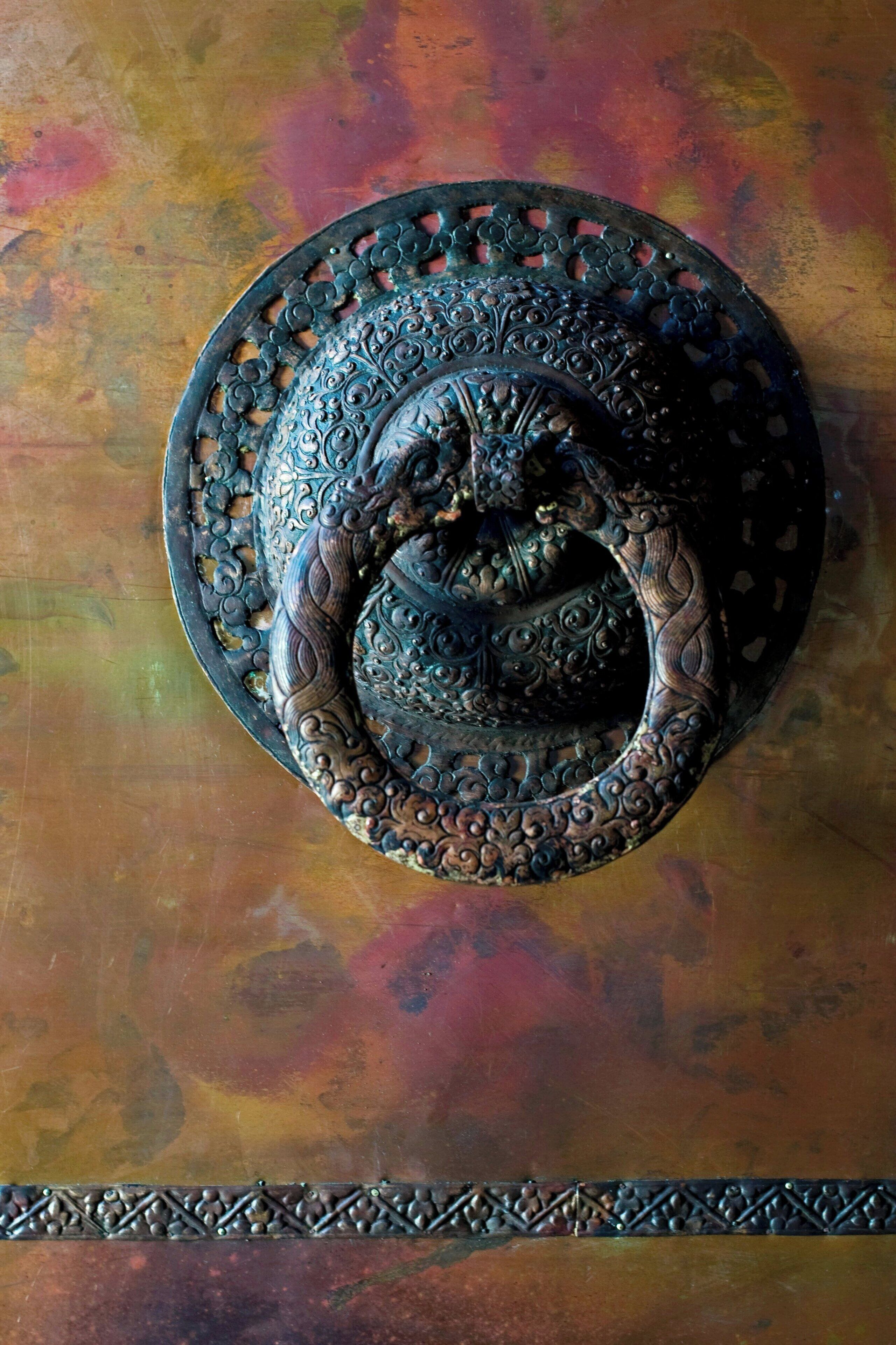 Een gedetailleerde metalen deurbel met ingewikkelde decoraties.