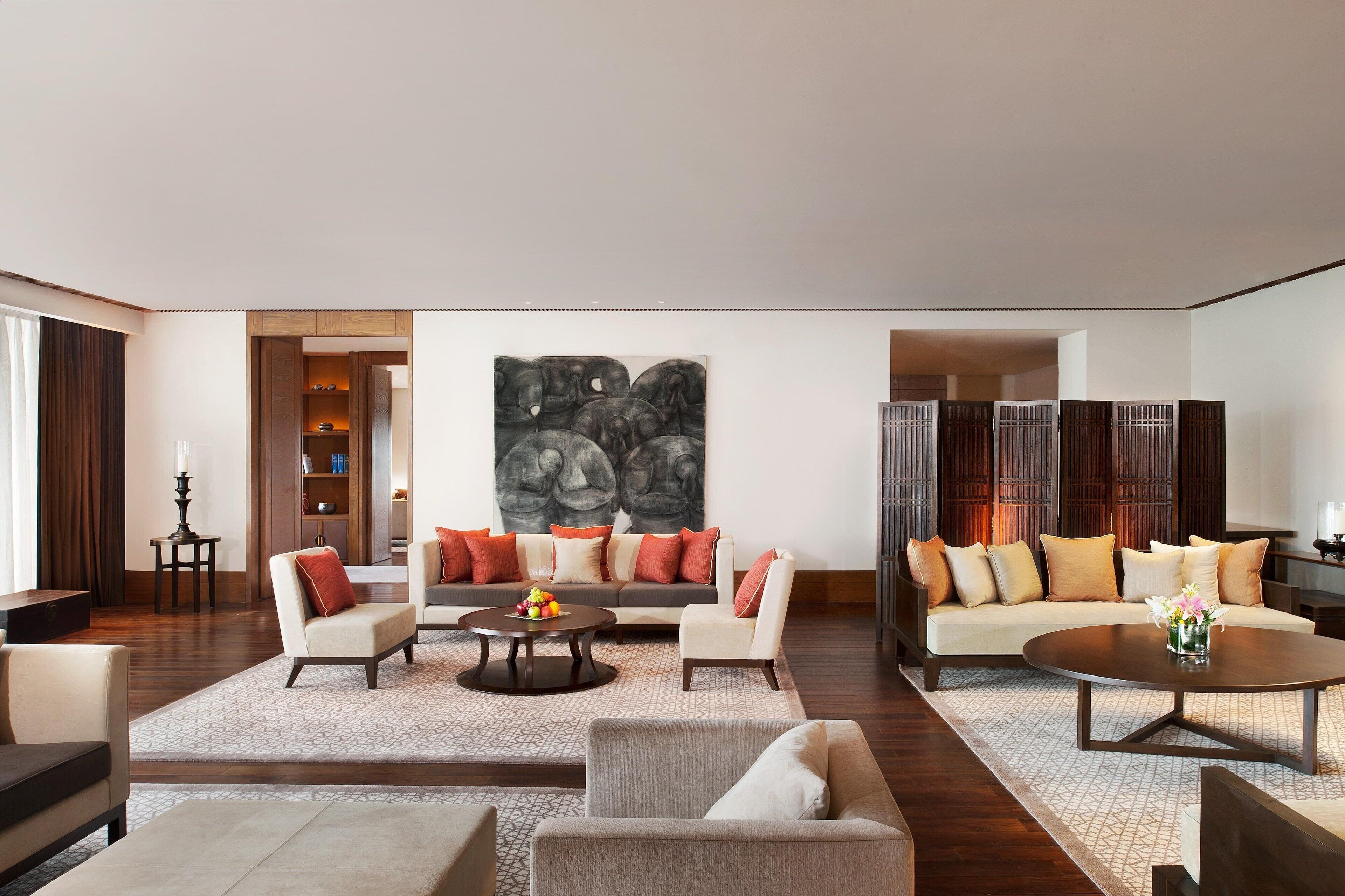 A spacious living room with a sofa set, a coffee table, and a large abstract painting on the wall.