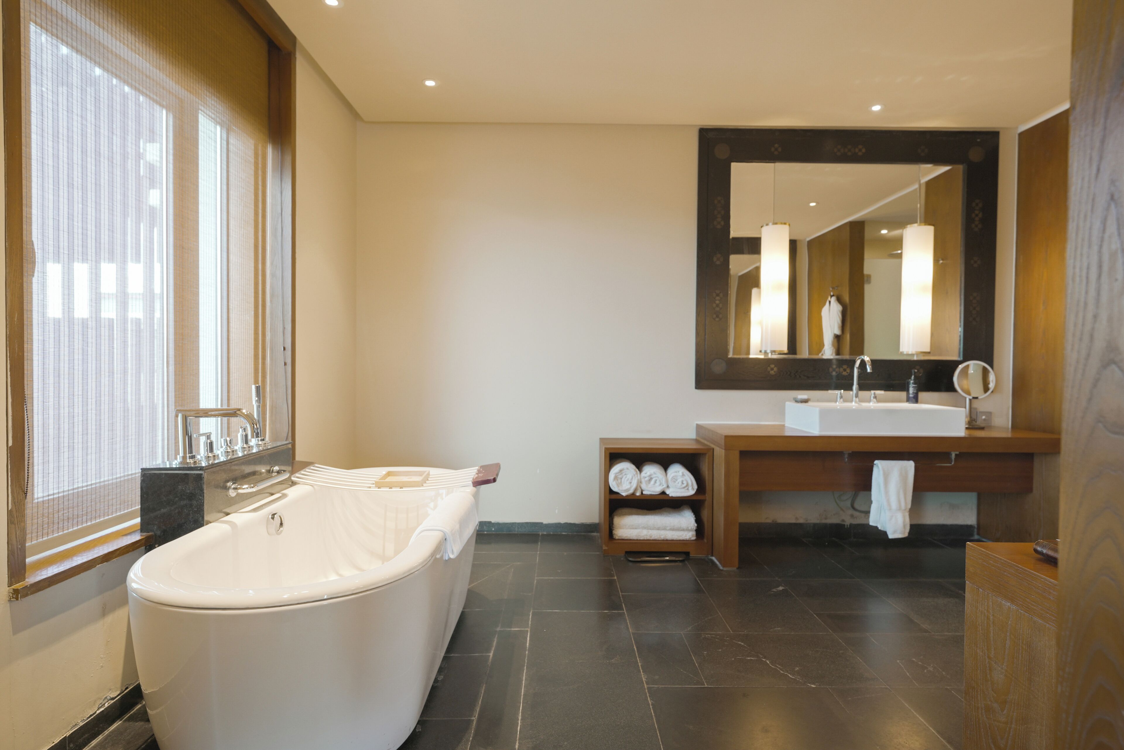 Ein modernes Badezimmer mit einer freistehenden Badewanne, einem Waschtisch mit Spiegel und einem Handtuchregal.