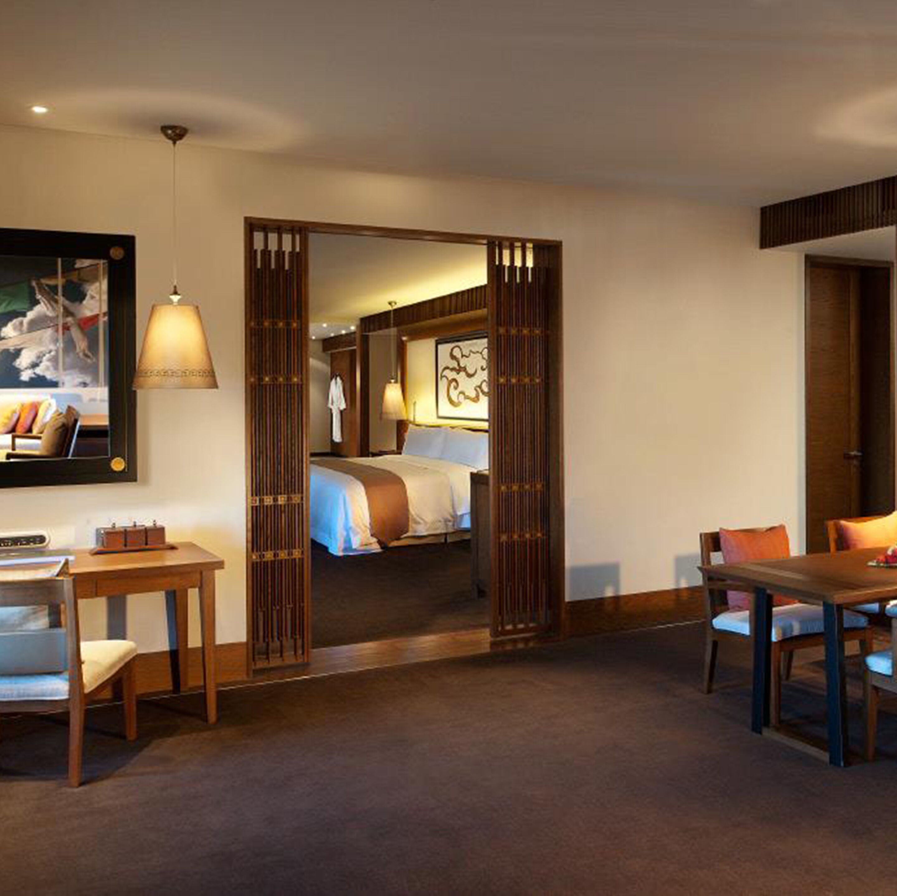 A hotel room with a bed, a desk, a chair, a table, and a large mirror.