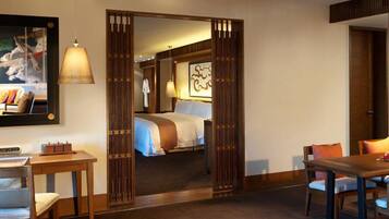 A hotel room with a bed, a desk, a chair, a table, and a large mirror.