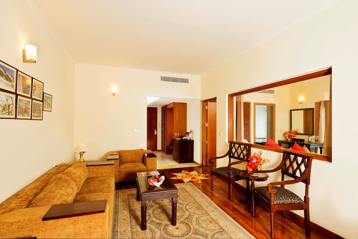 Una sala de estar con sofá, sillón, mesa de centro y un espejo que refleja la habitación.
