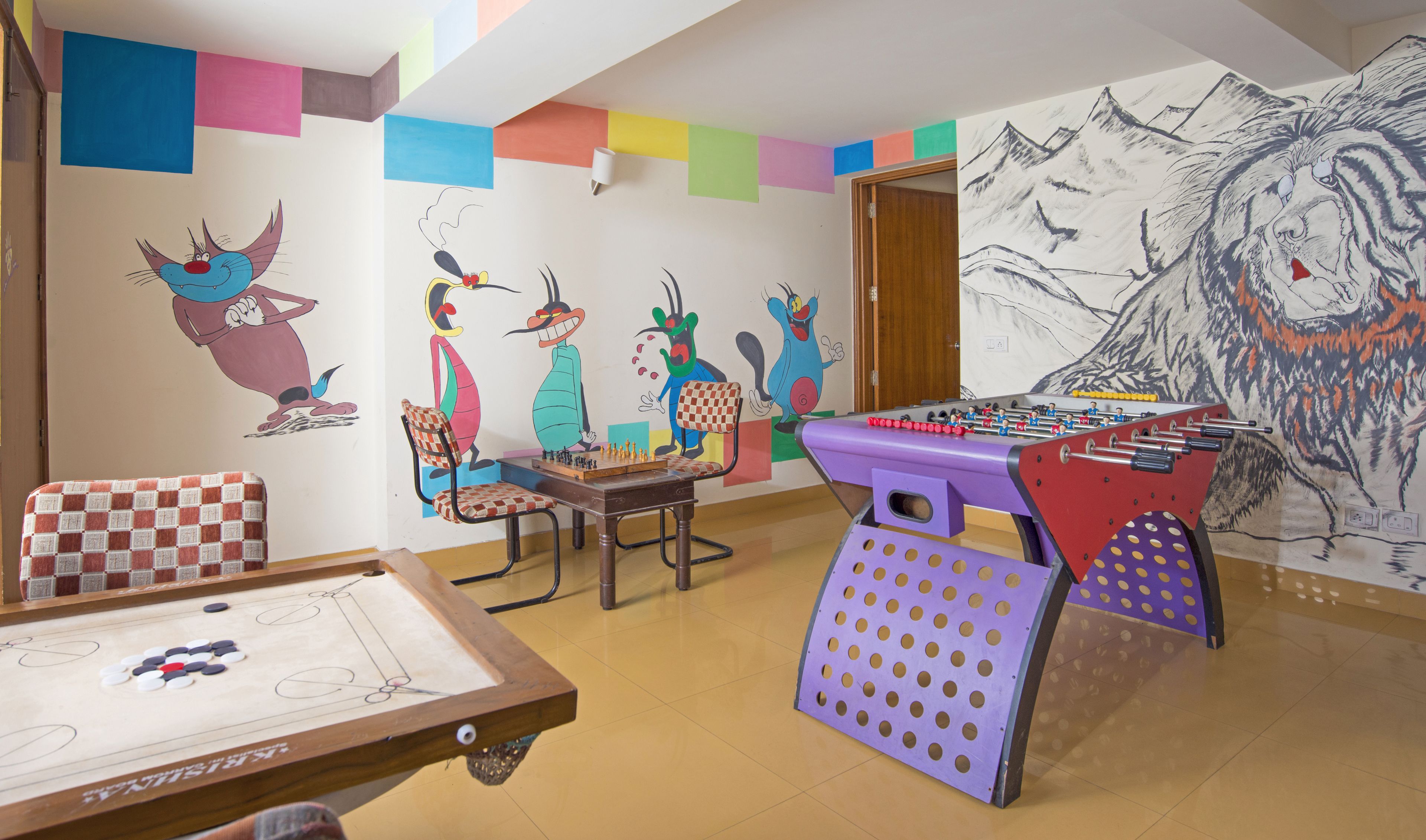A room with a foosball table, a chessboard, and a table tennis table.