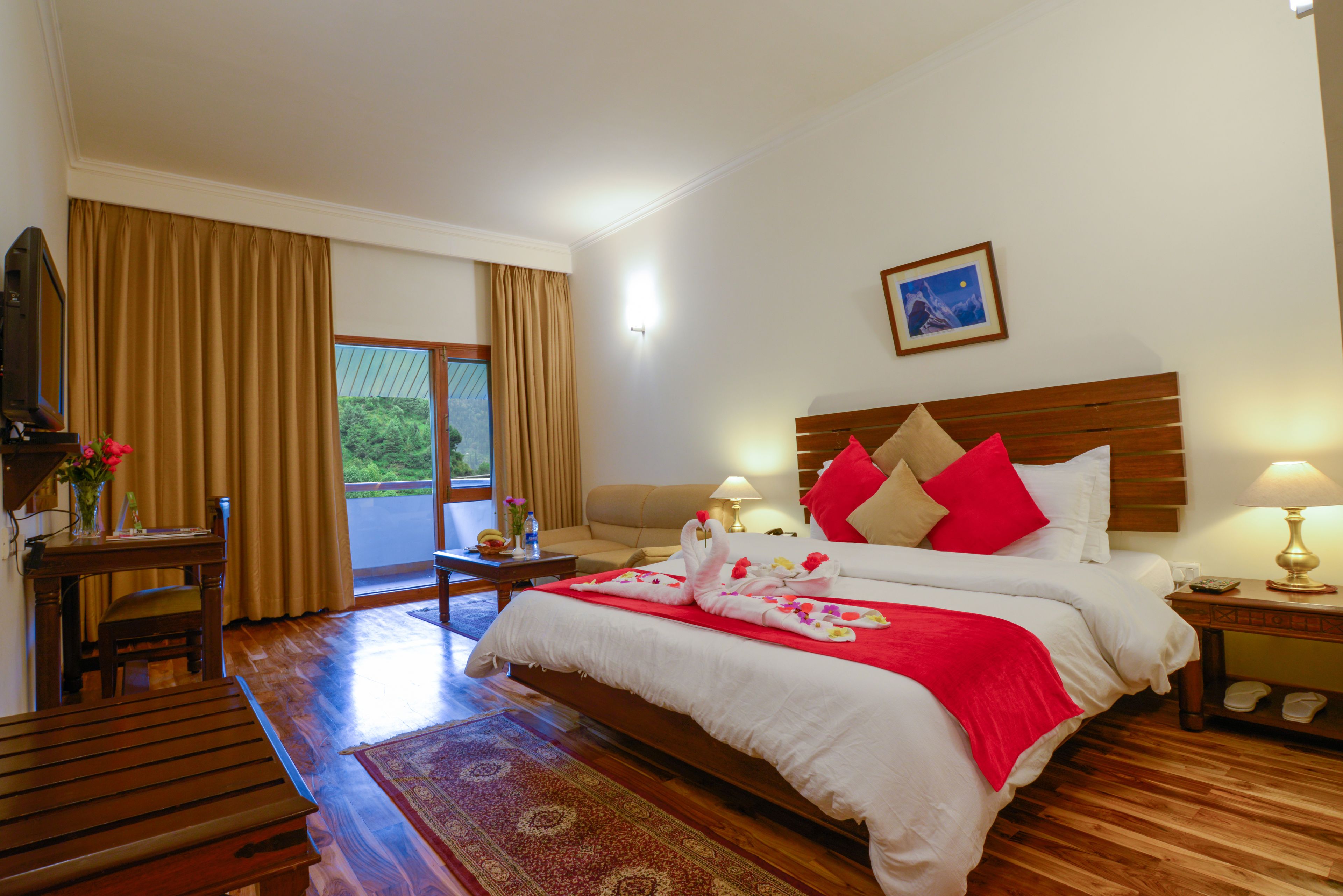 Un dormitorio amplio con una cama grande, un escritorio de madera, una silla y un televisor.