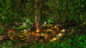 An outdoor dining area with tables and chairs set up among trees, surrounded by greenery. - Solang Valley Resort (Manali)