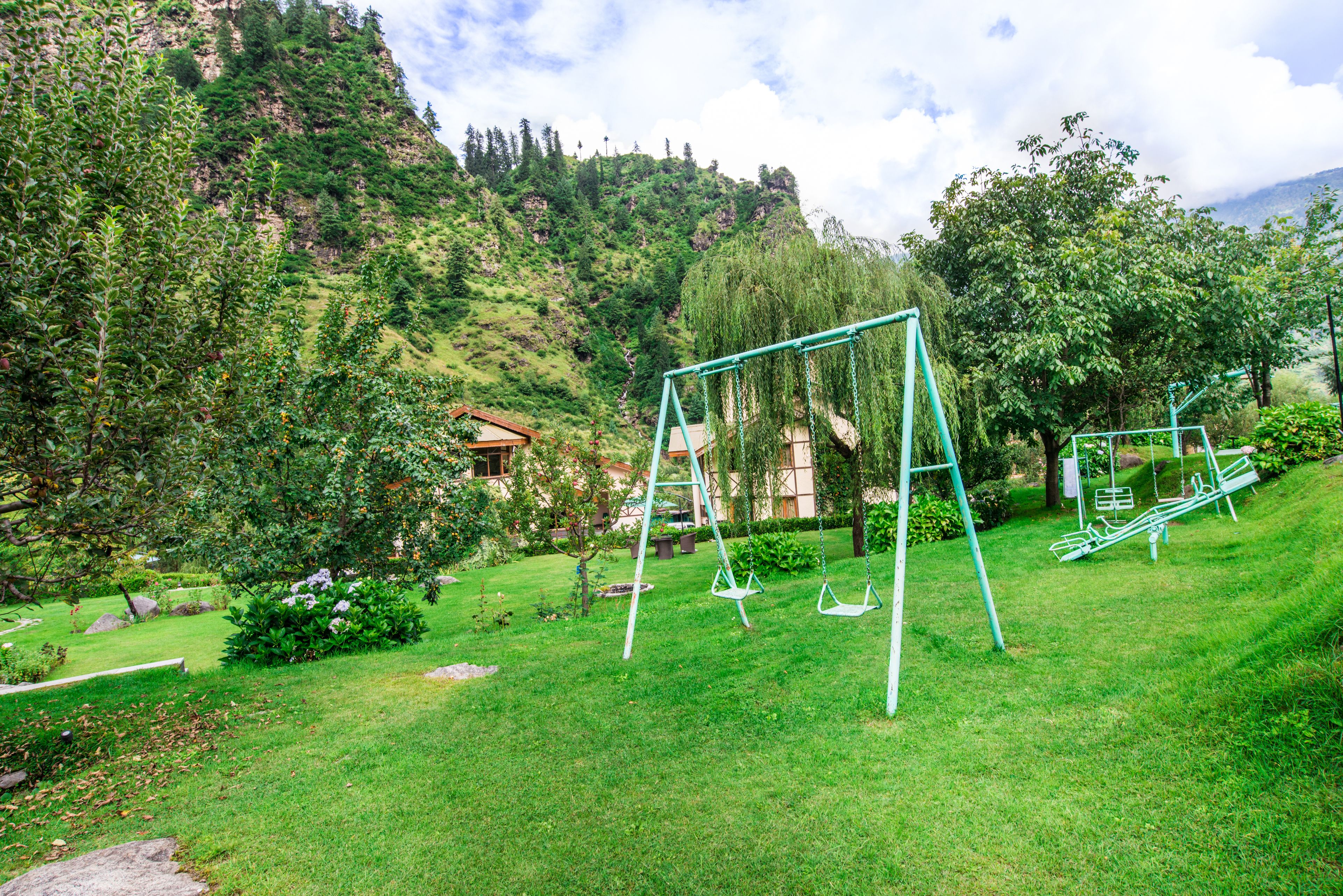 A grassy area with swings and a building in the background.