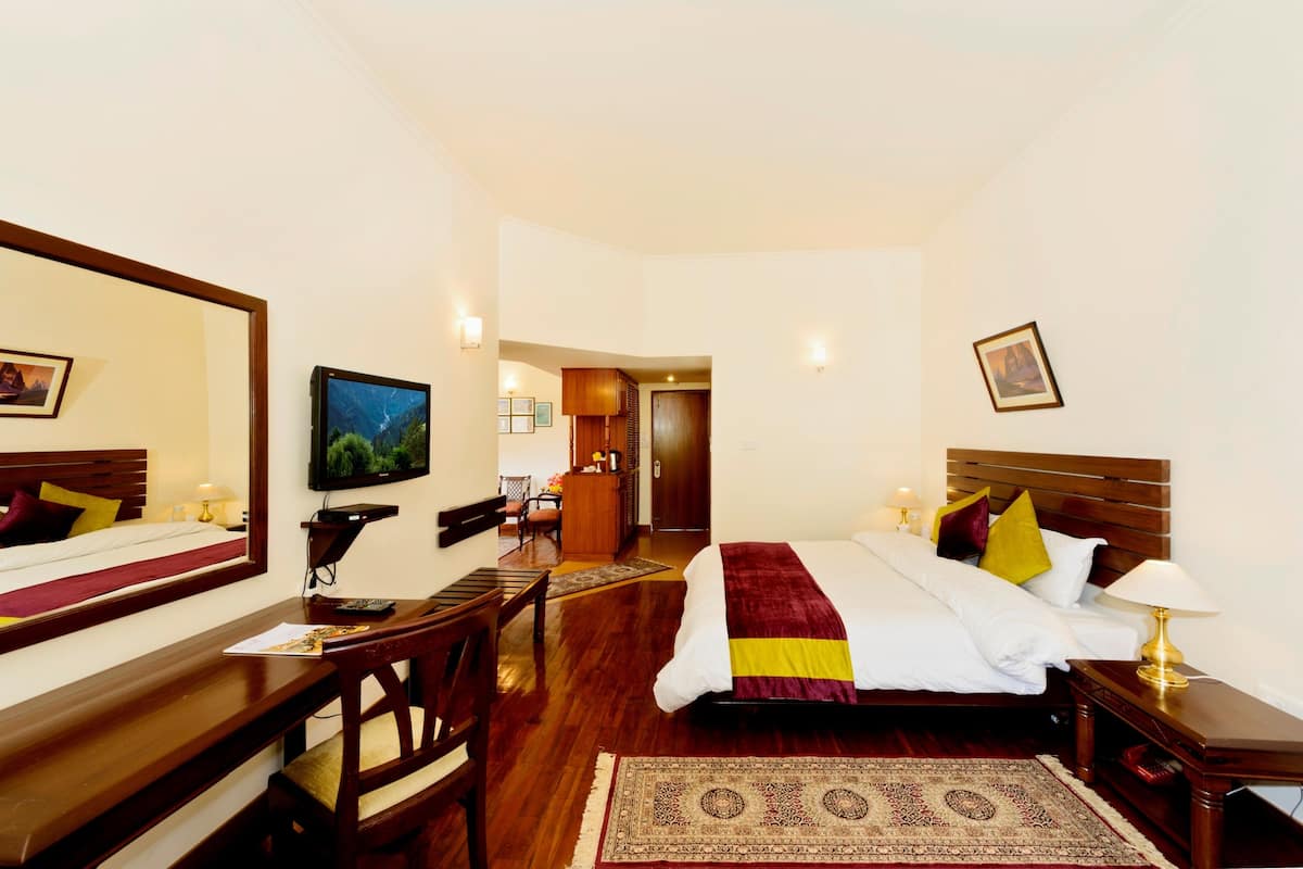 Habitación de hotel con cama, escritorio, silla, televisor y espejo.