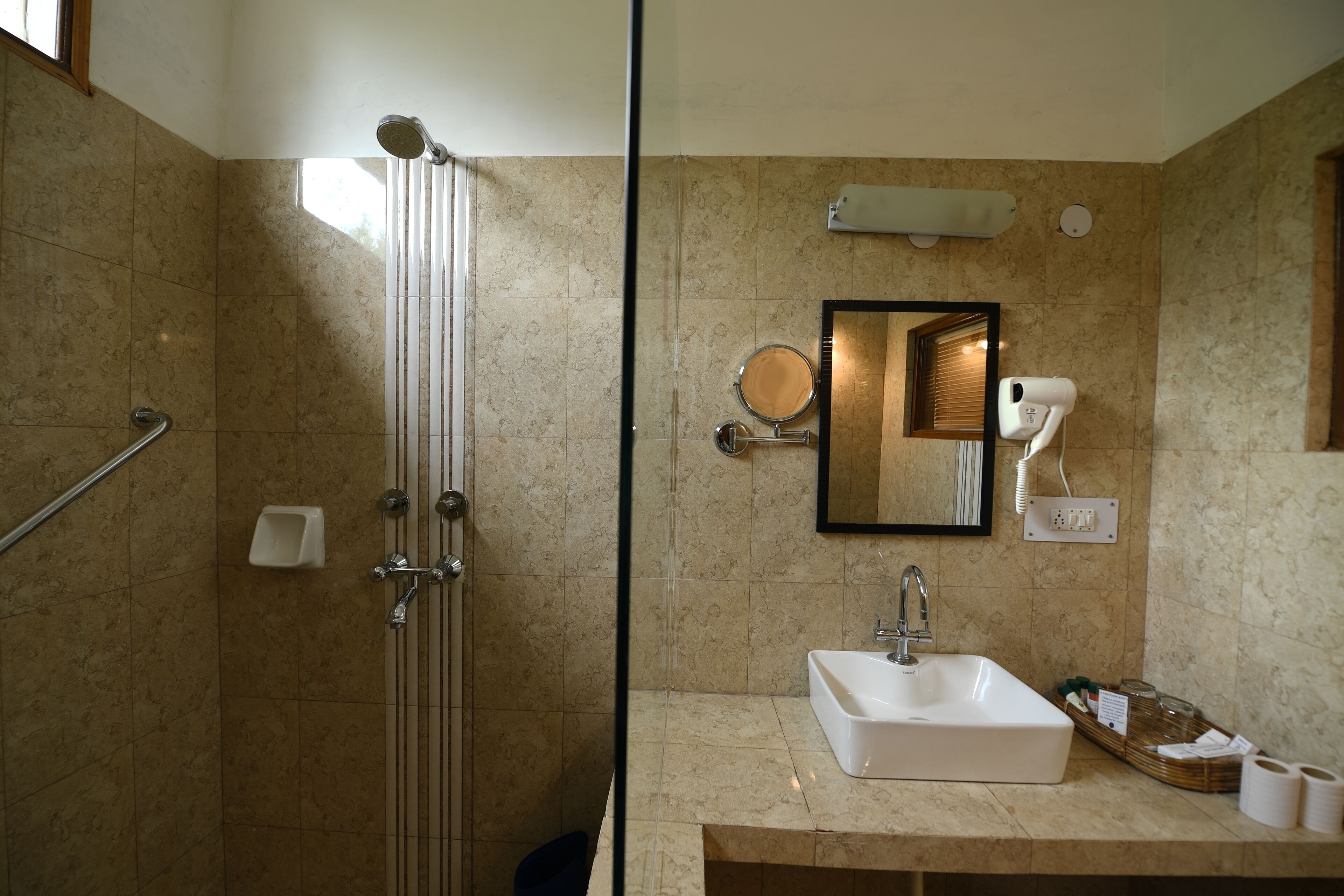 Ein modernes Badezimmer mit Duschkabine aus Glas, Waschbecken mit Spiegel und Haartrockner auf der Ablagefläche.