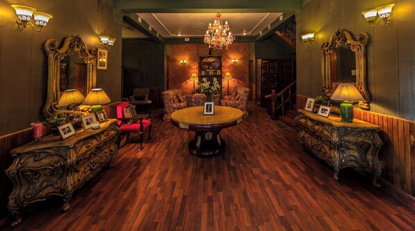 Una habitación con piso de madera, muebles ornamentales, un candelabro y apliques de pared.