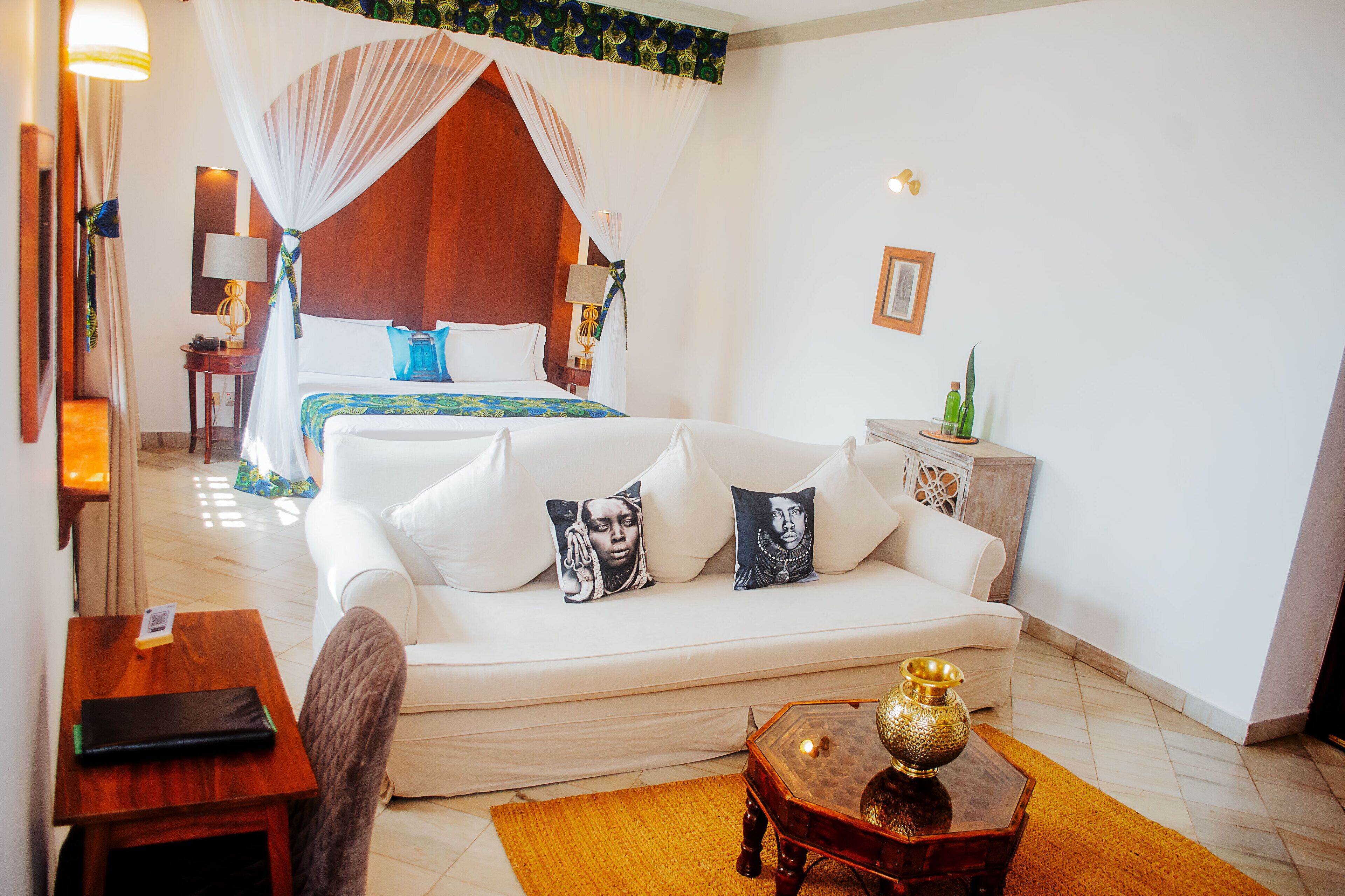 Une chambre d’hôtel avec un lit, un canapé, une petite table et une table de chevet.