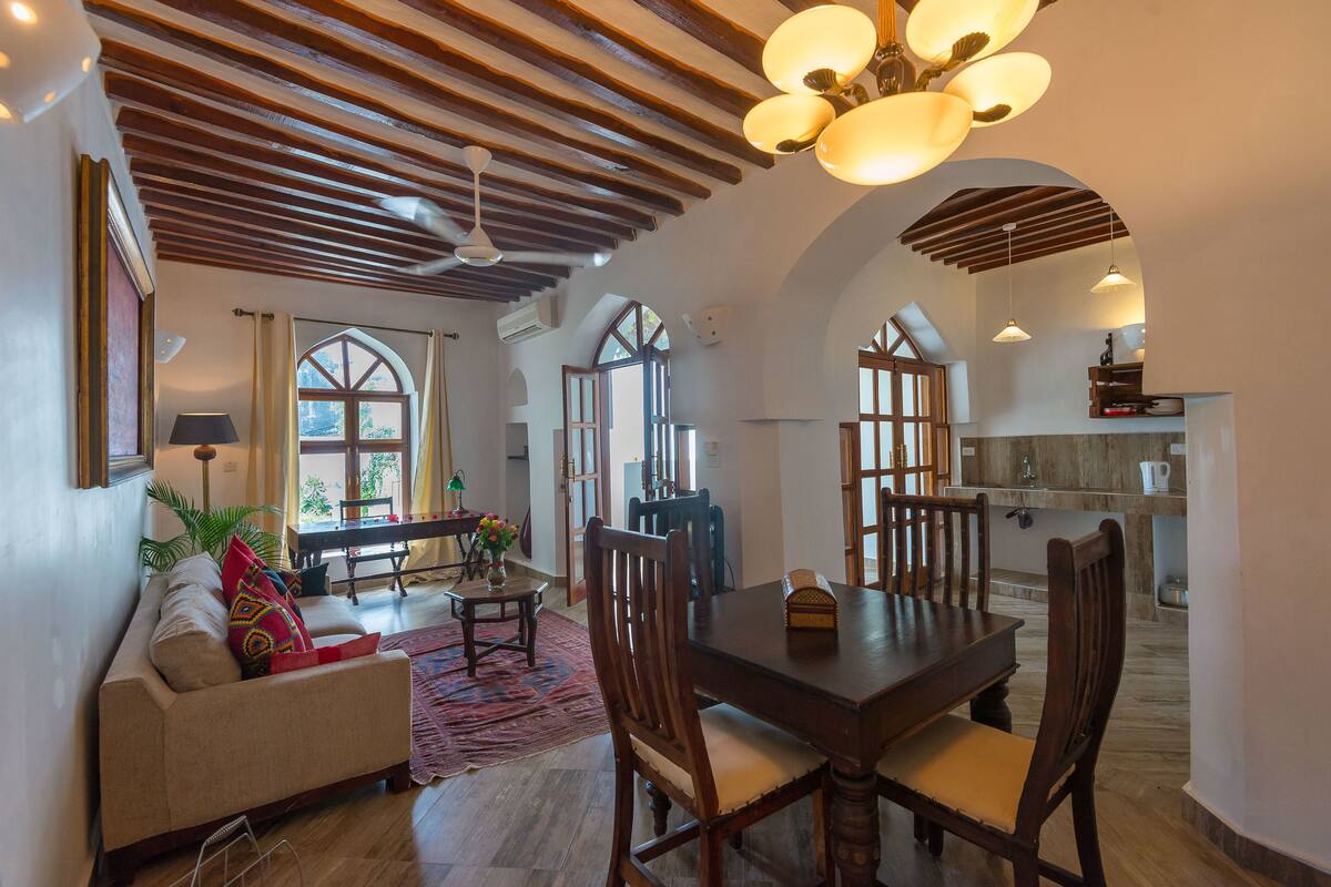 Amplia sala de estar con mesa de comedor de madera, asientos cómodos y vista a la cocina.