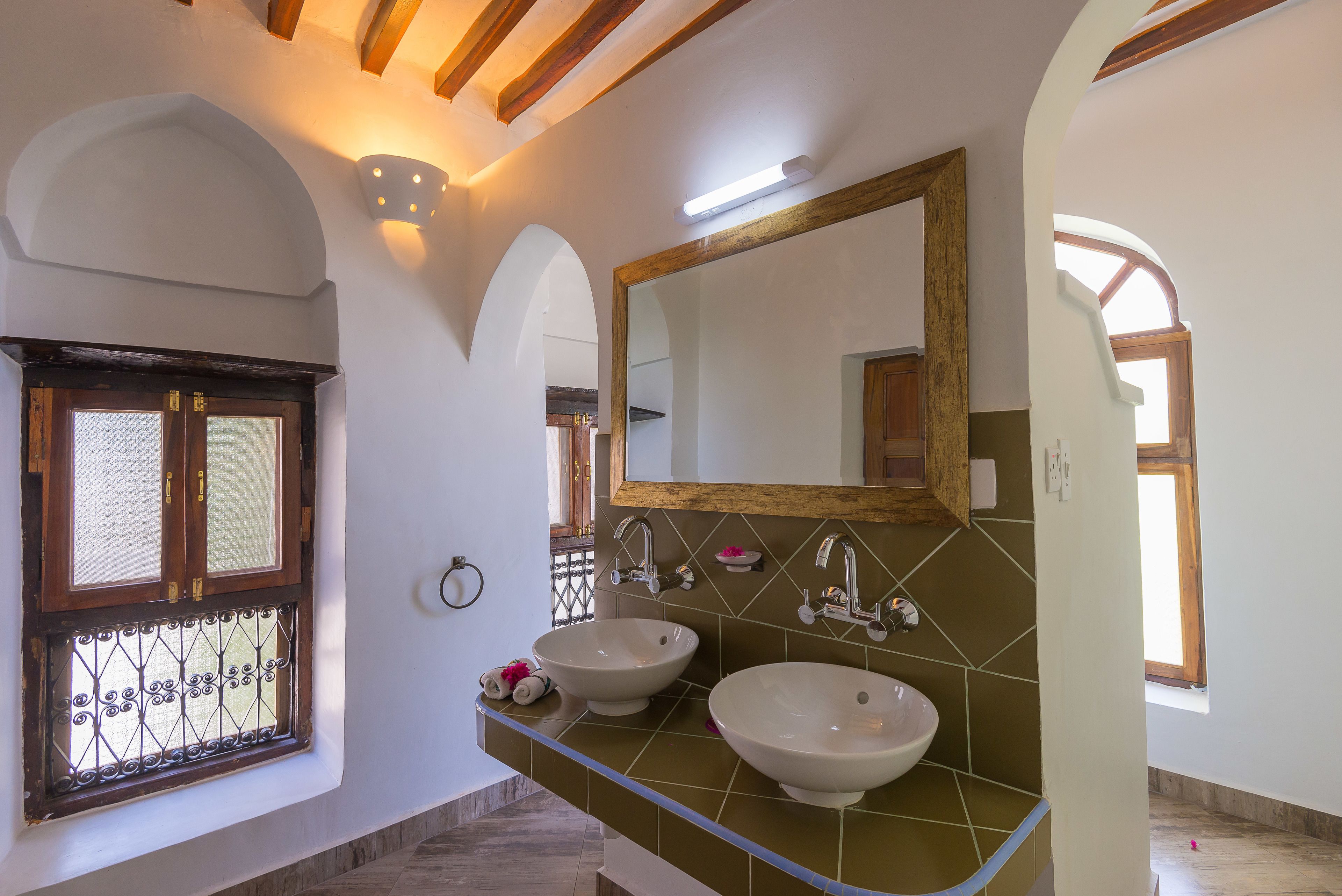 Un baño con dos lavamanos, un espejo grande y una ventana con marco de madera.