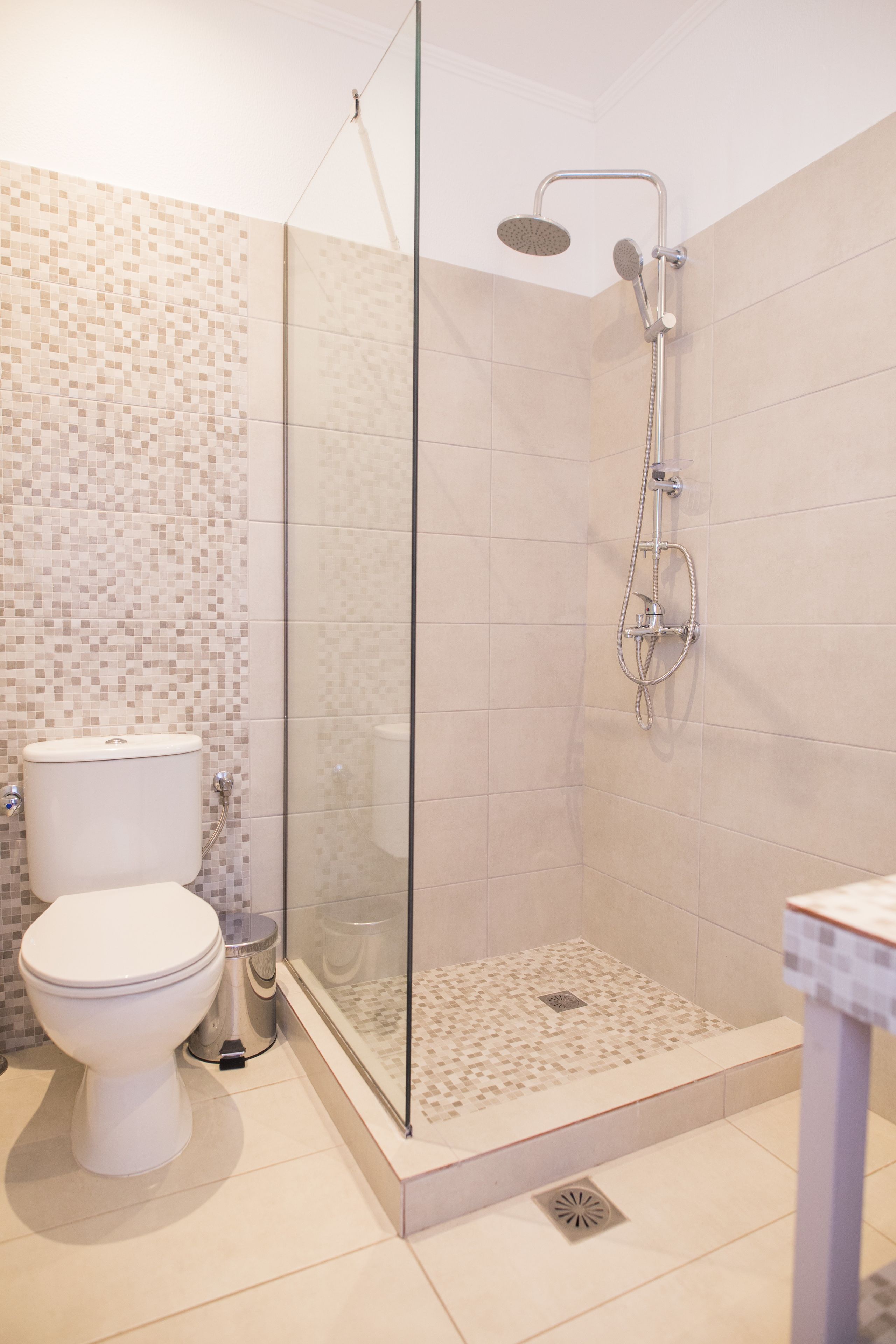 Een moderne badkamer met een douchecabine van glas, een toilet en een wastafel.