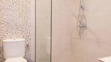 Een moderne badkamer met een douchecabine van glas, een toilet en een wastafel.