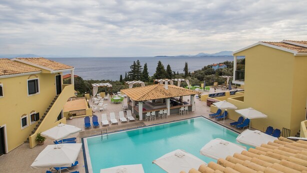 Un área de piscina con sillones de descanso y sombrillas, un espacio de estar techado y vistas al mar.