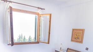 Una cama bien tendida con sábanas blancas, cabecera de madera y ventana con cortinas.