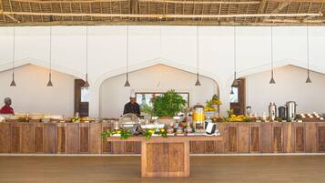 A buffet setup with a wooden counter, hanging pendant lights, and a central decorative plant.