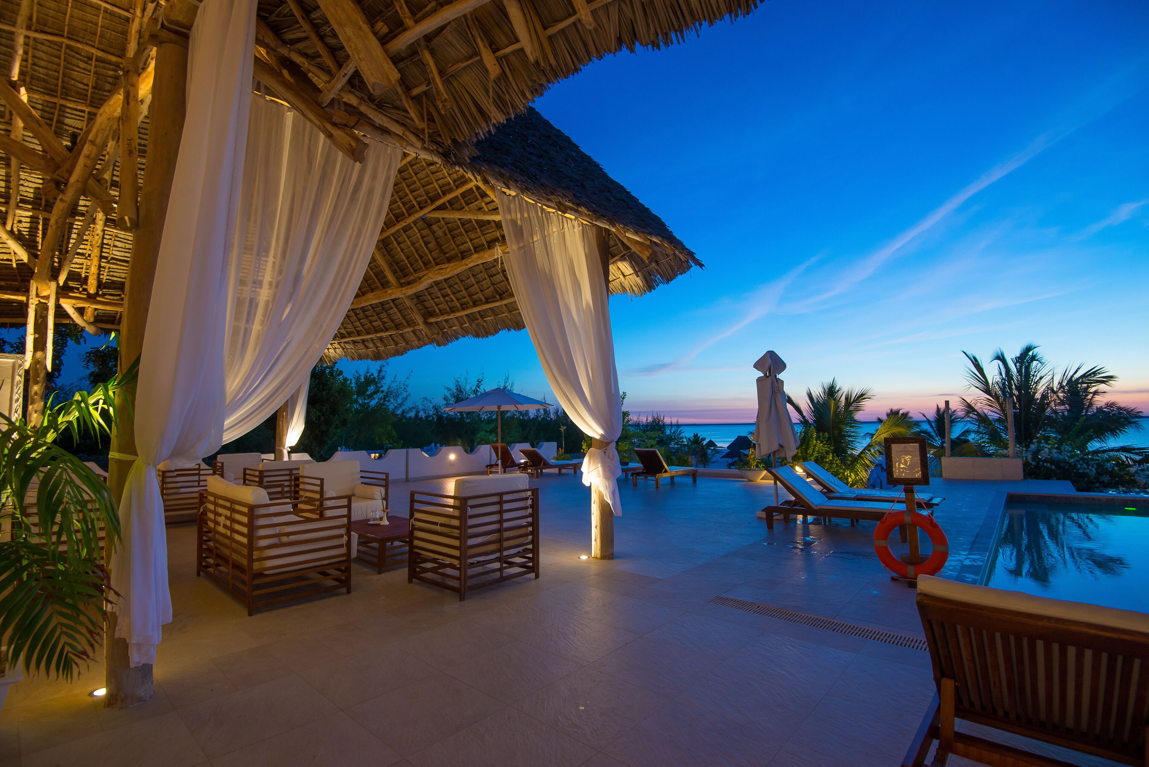 A poolside area with lounge chairs, a covered seating area, and a lifebuoy.