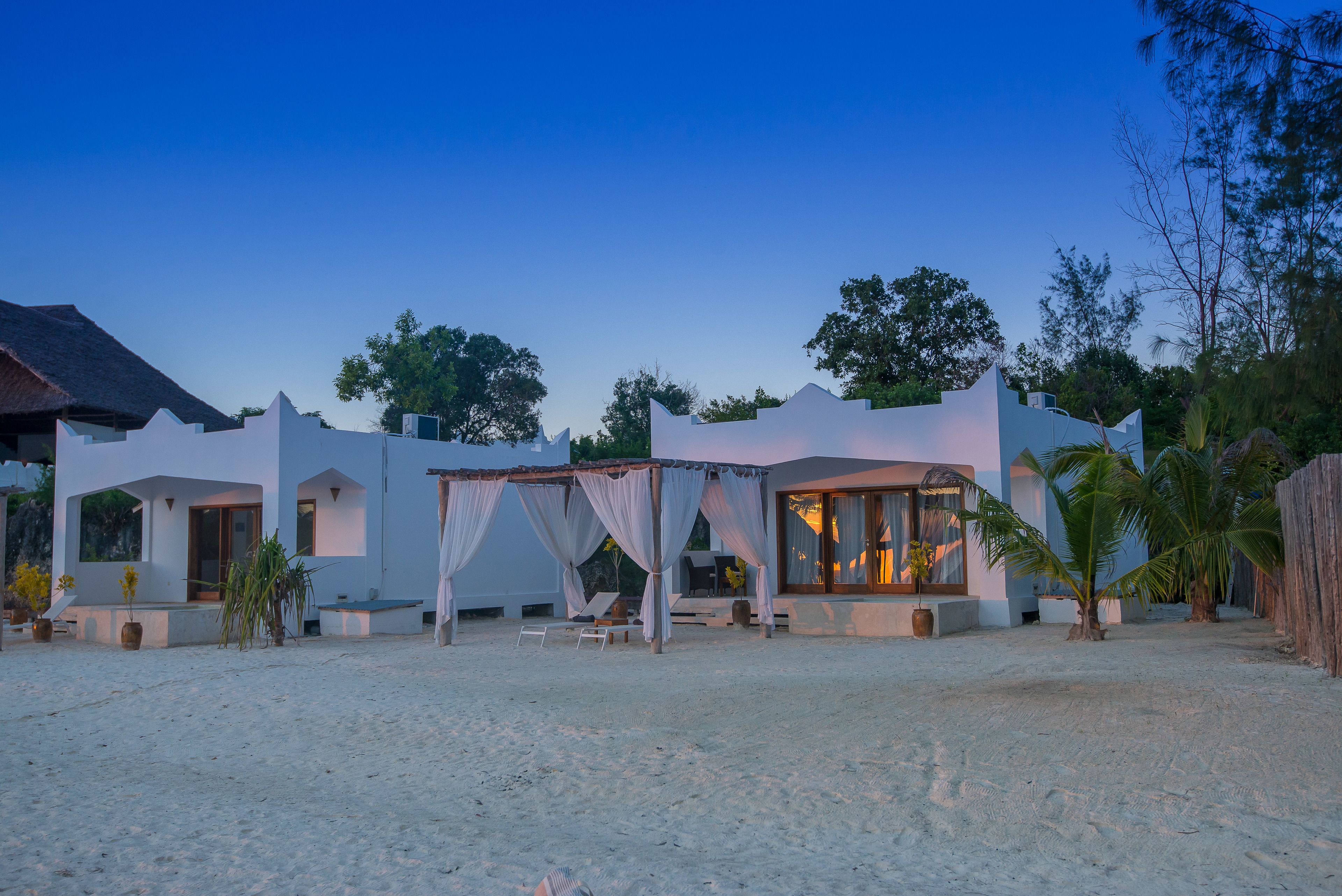 A beachfront property with a covered outdoor seating area, a pool, and a large window overlooking the ocean.