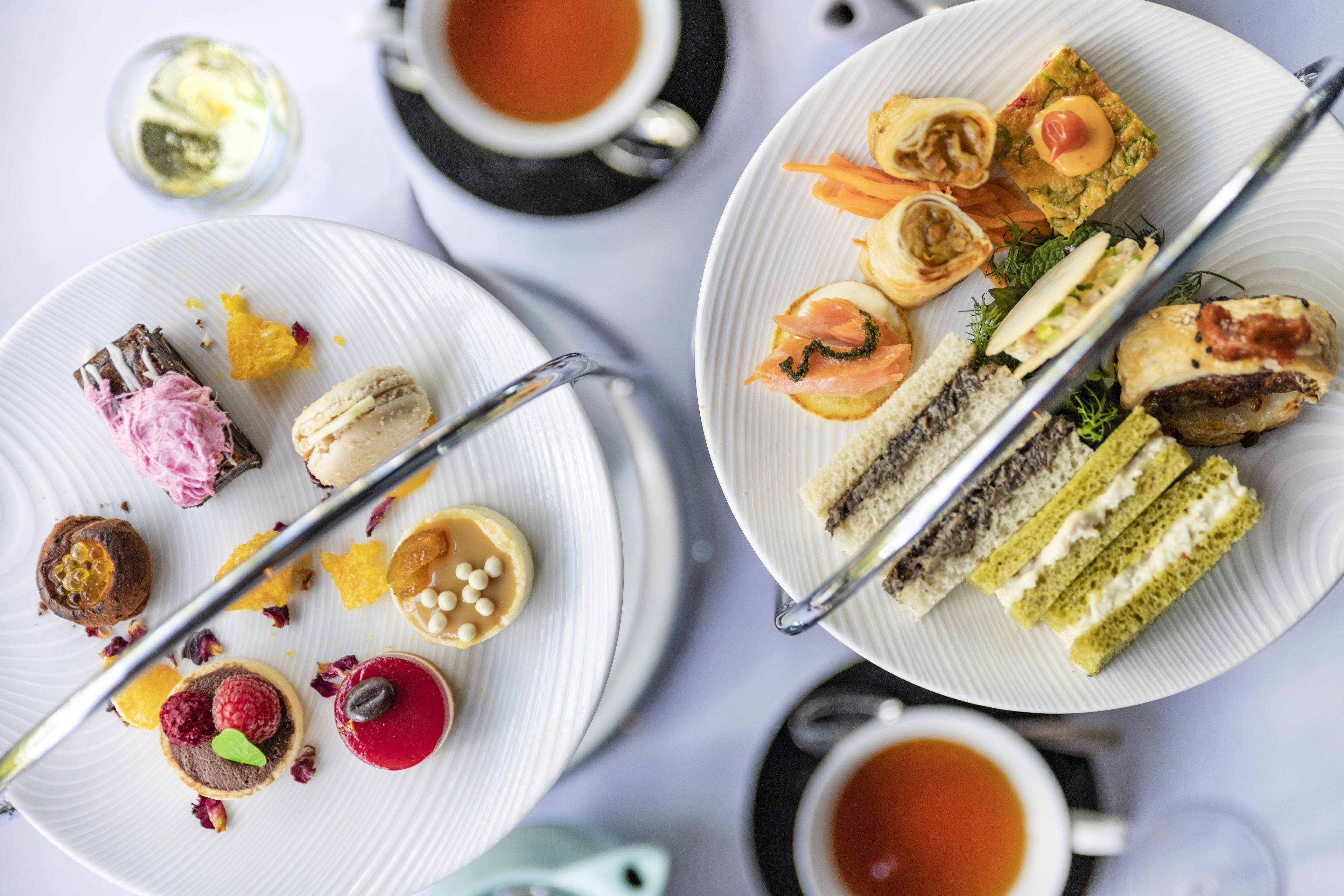 A table with various desserts and tea cups.