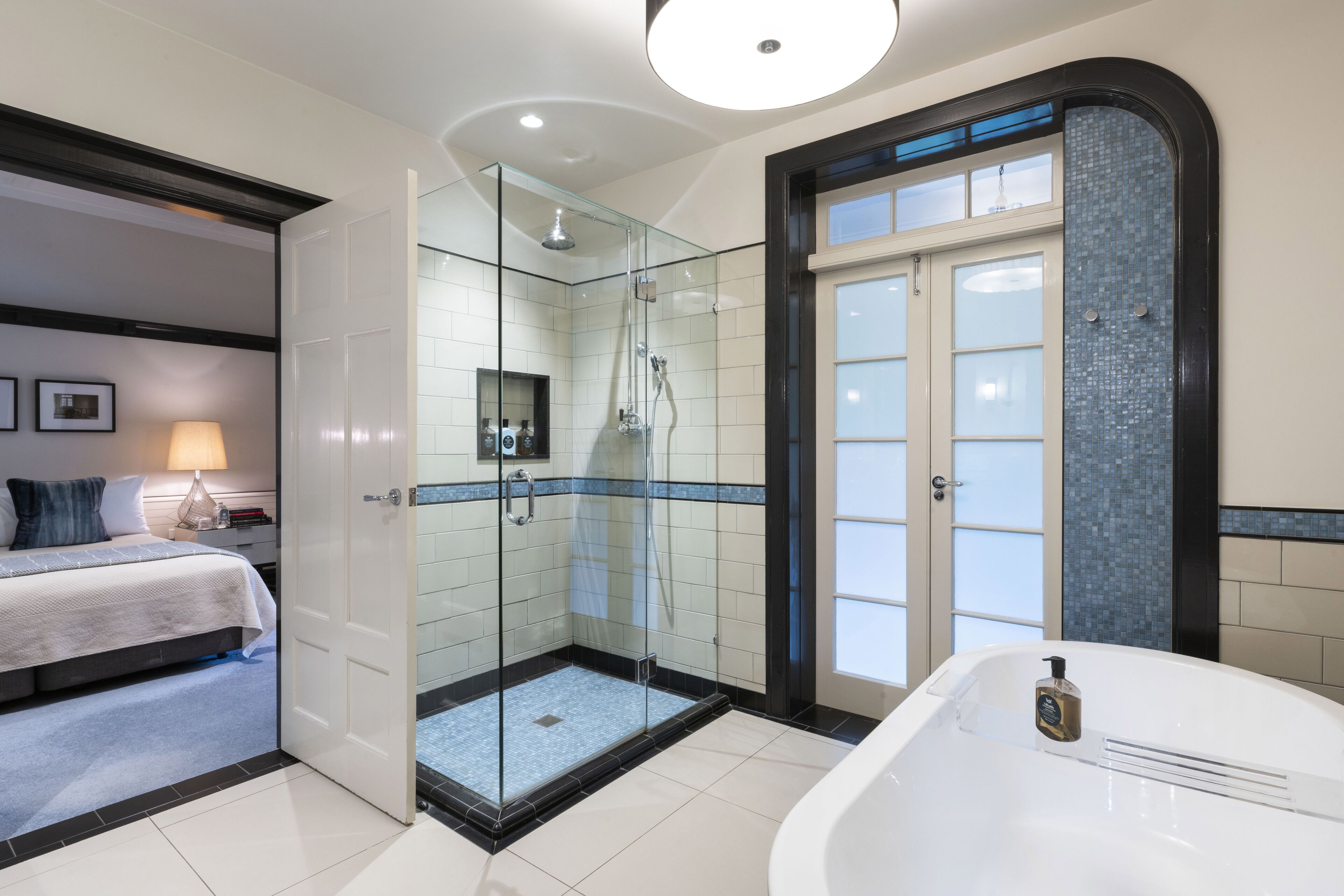 Un baño moderno con ducha de vidrio, bañera independiente y cabina de ducha separada.