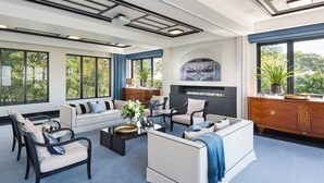 Un salón amplio con sofá, sillones, una mesa de centro y chimenea.