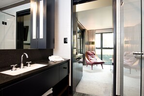 A modern bathroom with a large mirror, a black countertop, and a white sink.