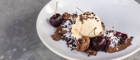 A dessert plate with ice cream, cherries, chocolate pieces, and shredded coconut.