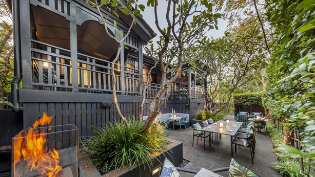 Un patio al aire libre con una chimenea, asientos y vistas a un edificio.