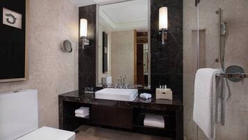 A modern bathroom with a white sink, dark marble countertop, and a large mirror.
