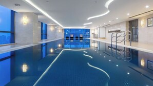 A modern indoor swimming pool with a clear view of the cityscape through large windows. - Courtyard by Marriott Suzhou (Suzhou)