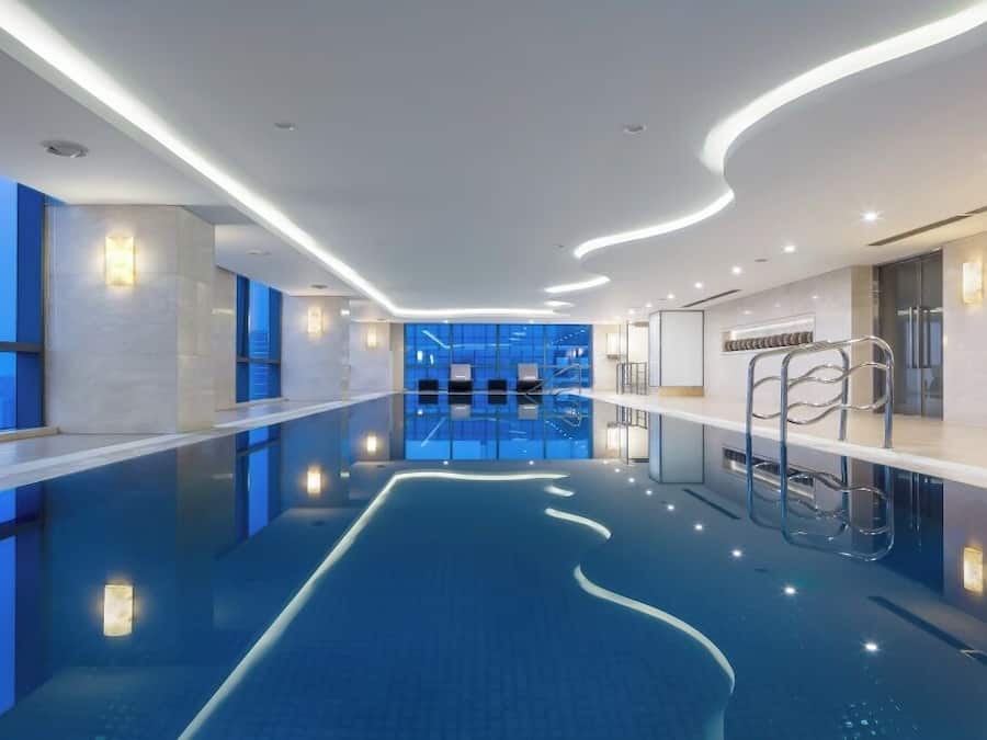 Piscina interior moderna com vista clara para a cidade através de grandes janelas.