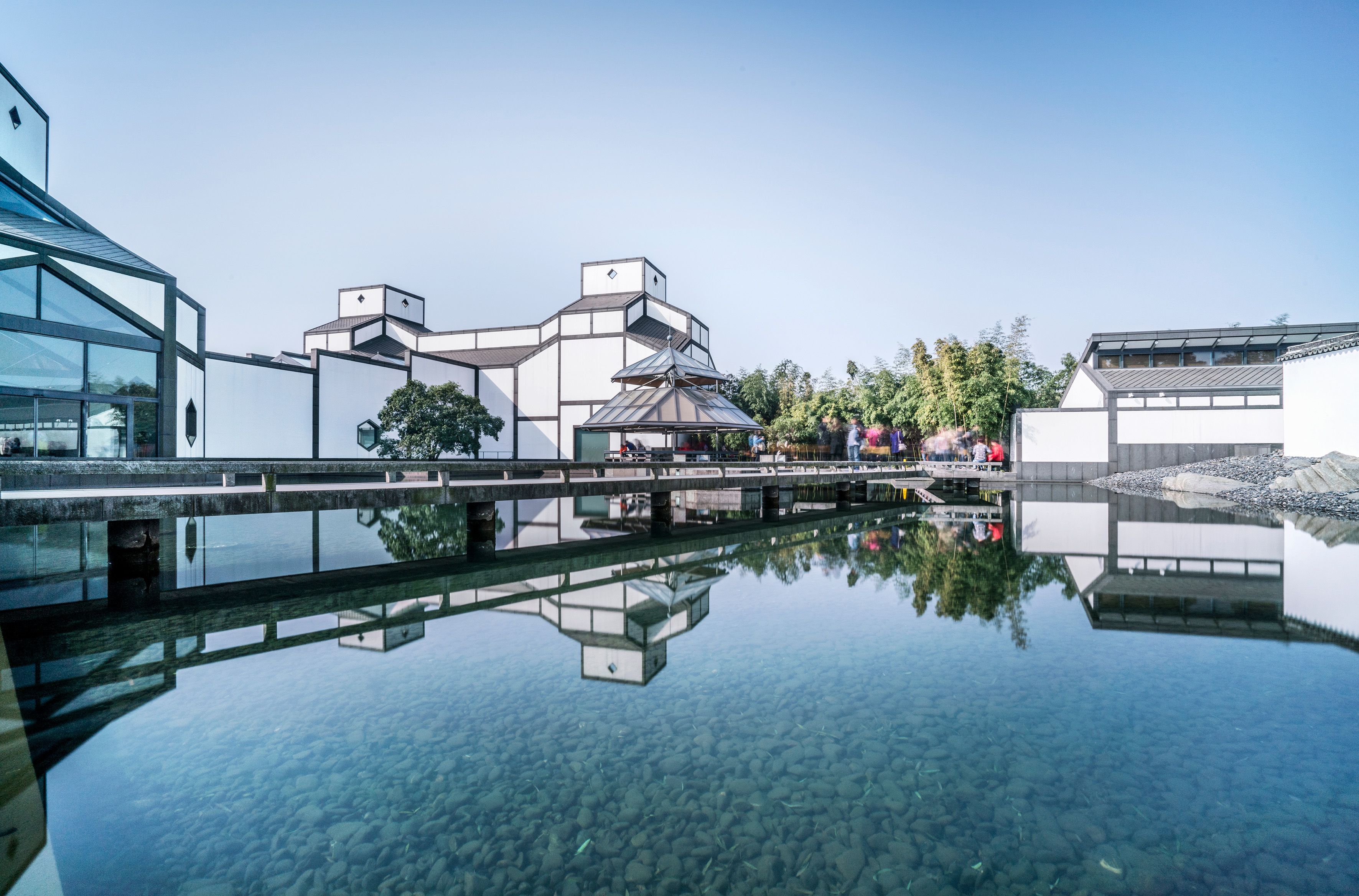 Un edificio moderno con fachada de vidrio y reflejo en el agua.