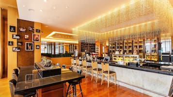 A modern bar area with a long counter, bar stools, and a display of various beverages.