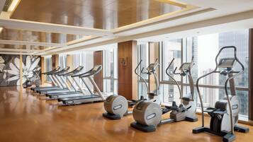 A gym with treadmills, ellipticals, and stationary bikes arranged in rows.