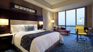 A hotel room with a large bed, two bedside tables with lamps, a desk with a chair, a small sofa, and a large window offering a city view. - Courtyard by Marriott Suzhou (Suzhou)