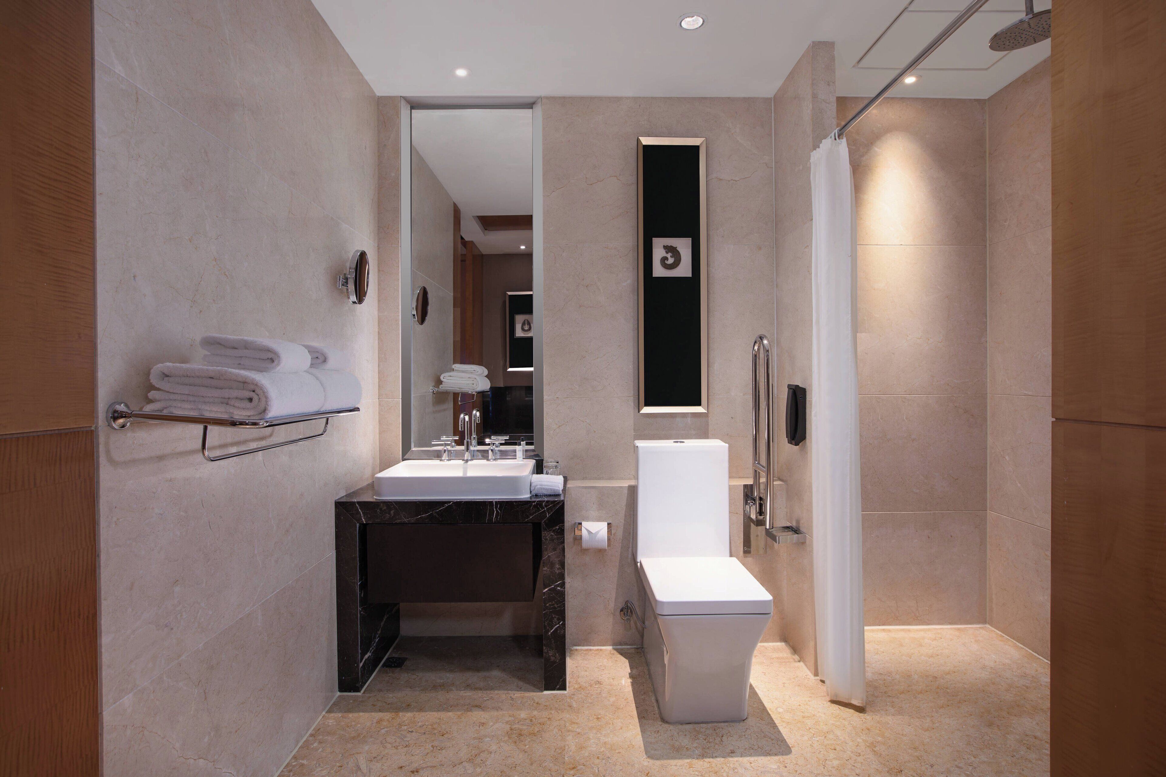 A modern bathroom with a marble sink, a toilet, and a shower area.