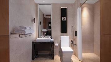 A modern bathroom with a marble sink, a toilet, and a shower area.