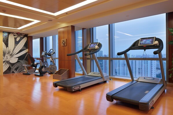 A modern gym with treadmills, a stationary bike, and a rowing machine. It features large windows with a city view. - Courtyard by Marriott Suzhou (Suzhou)
