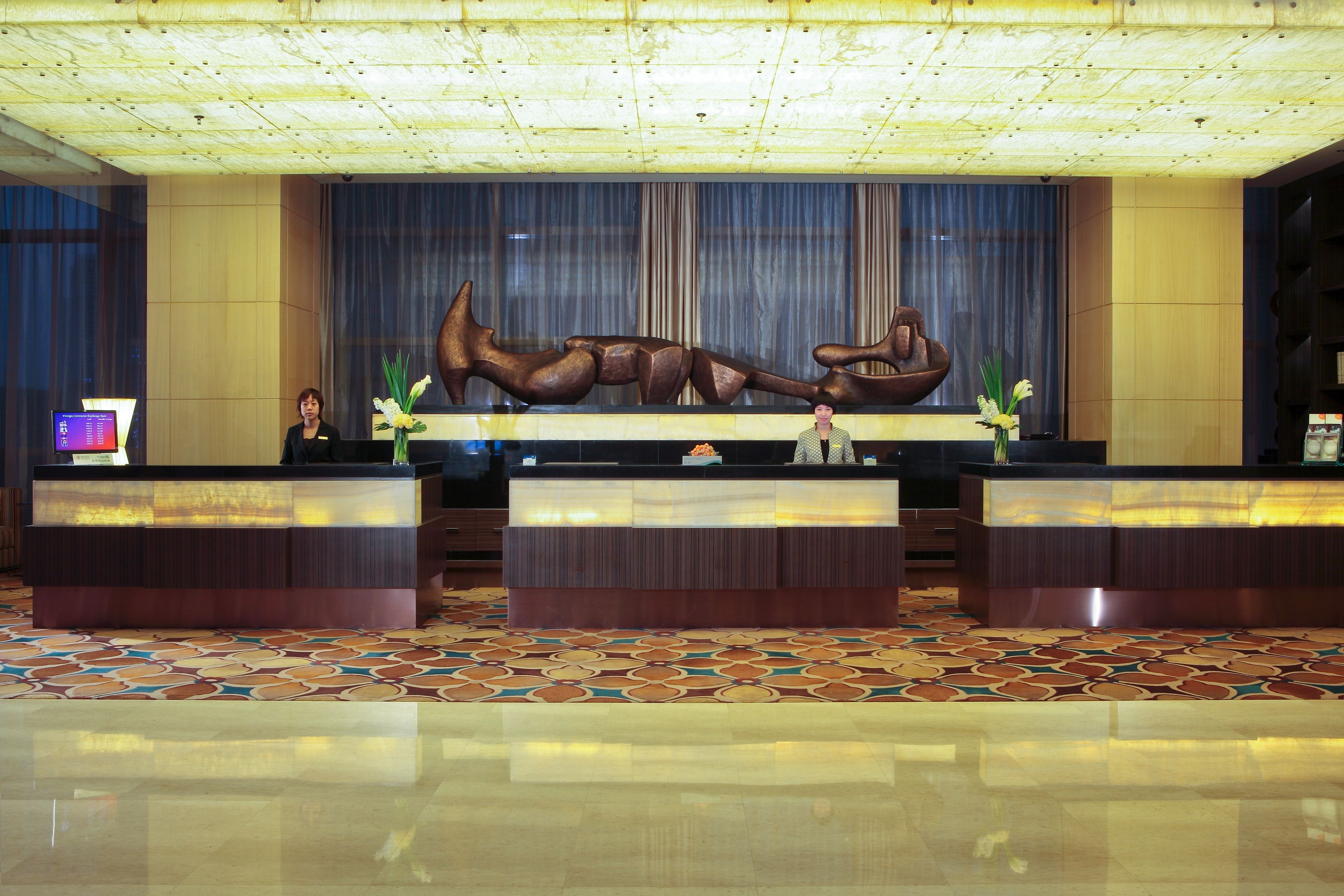 A reception area with a large, abstract sculpture, a reception desk, and a patterned floor.