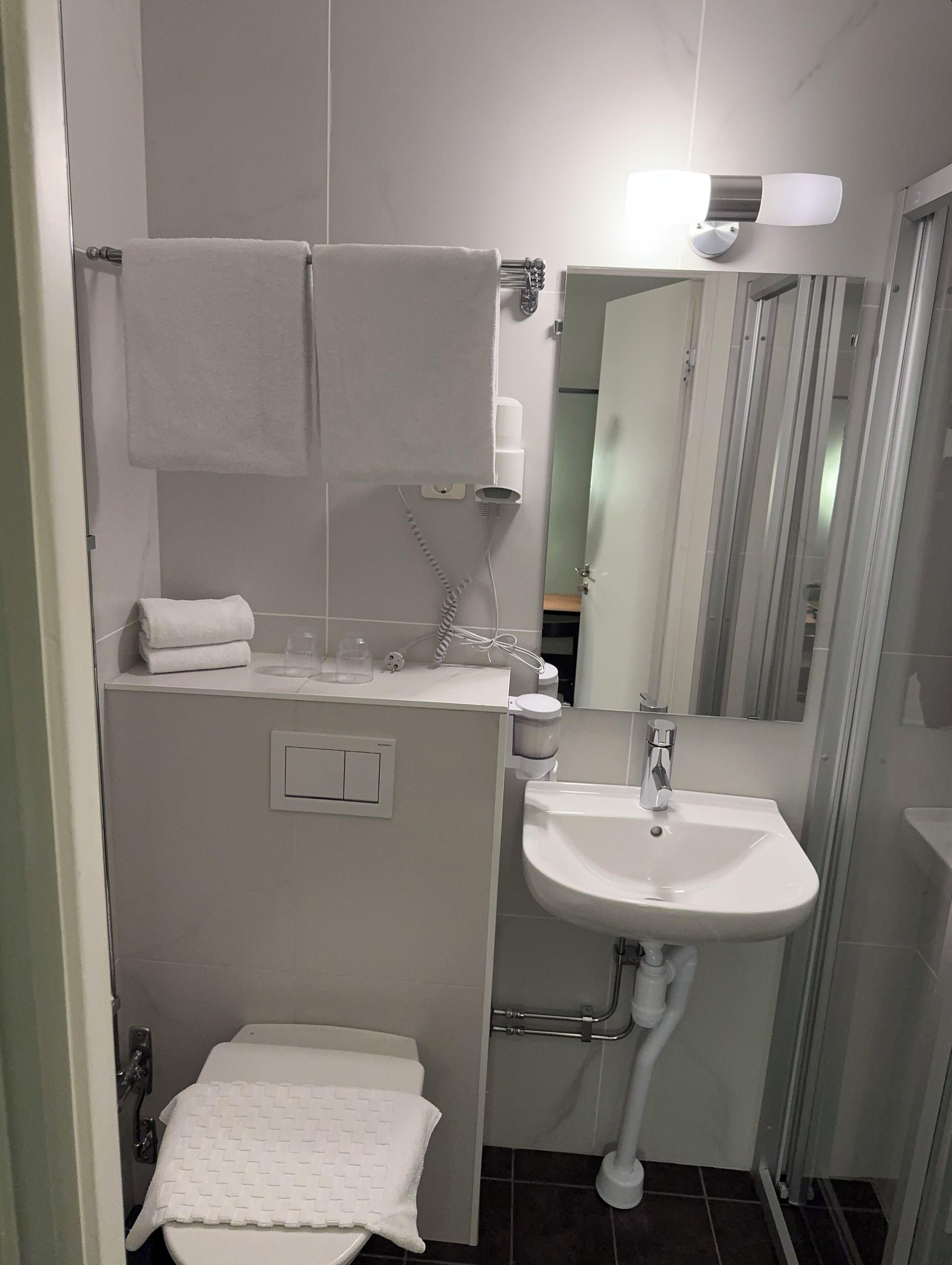 A bathroom with a white sink, a mirror, a towel rack, and a toilet.