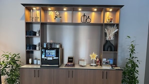 A reception desk with a coffee machine, a small seating area, and decorative items.