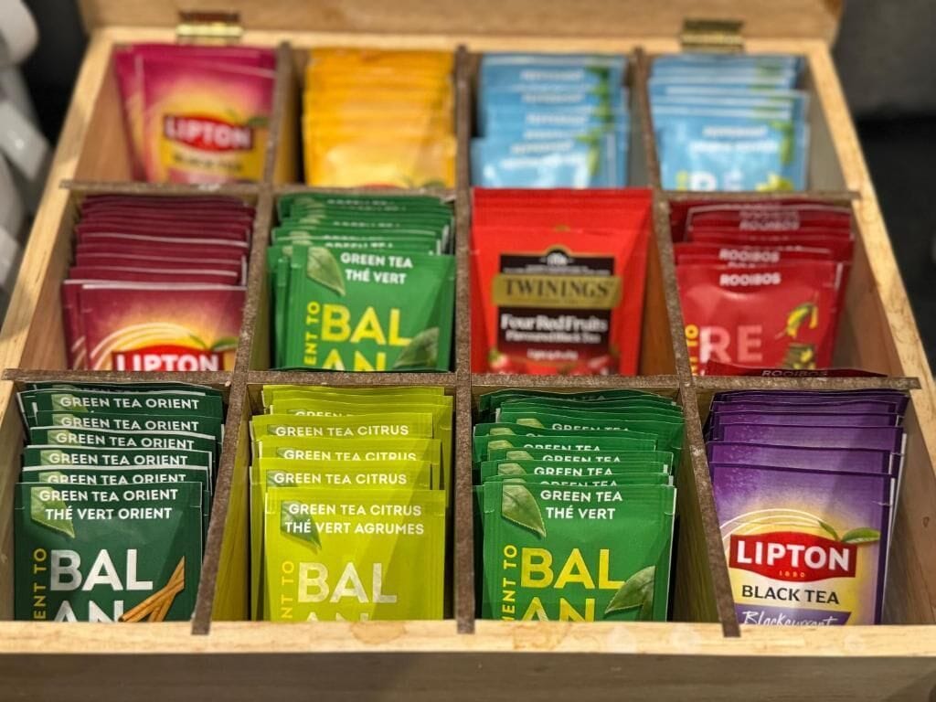 Een houten doos gevuld met verschillende Lipton theezakjes in uiteenlopende smaken.