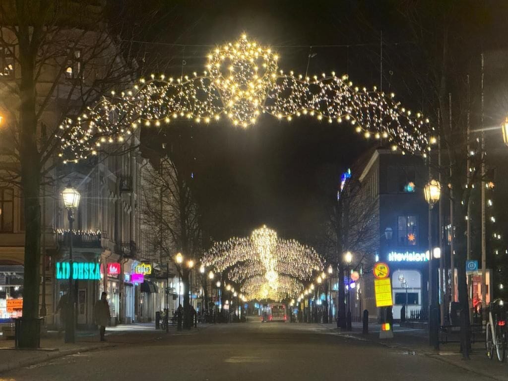 A street at night with string lights and a large arch of lights above.