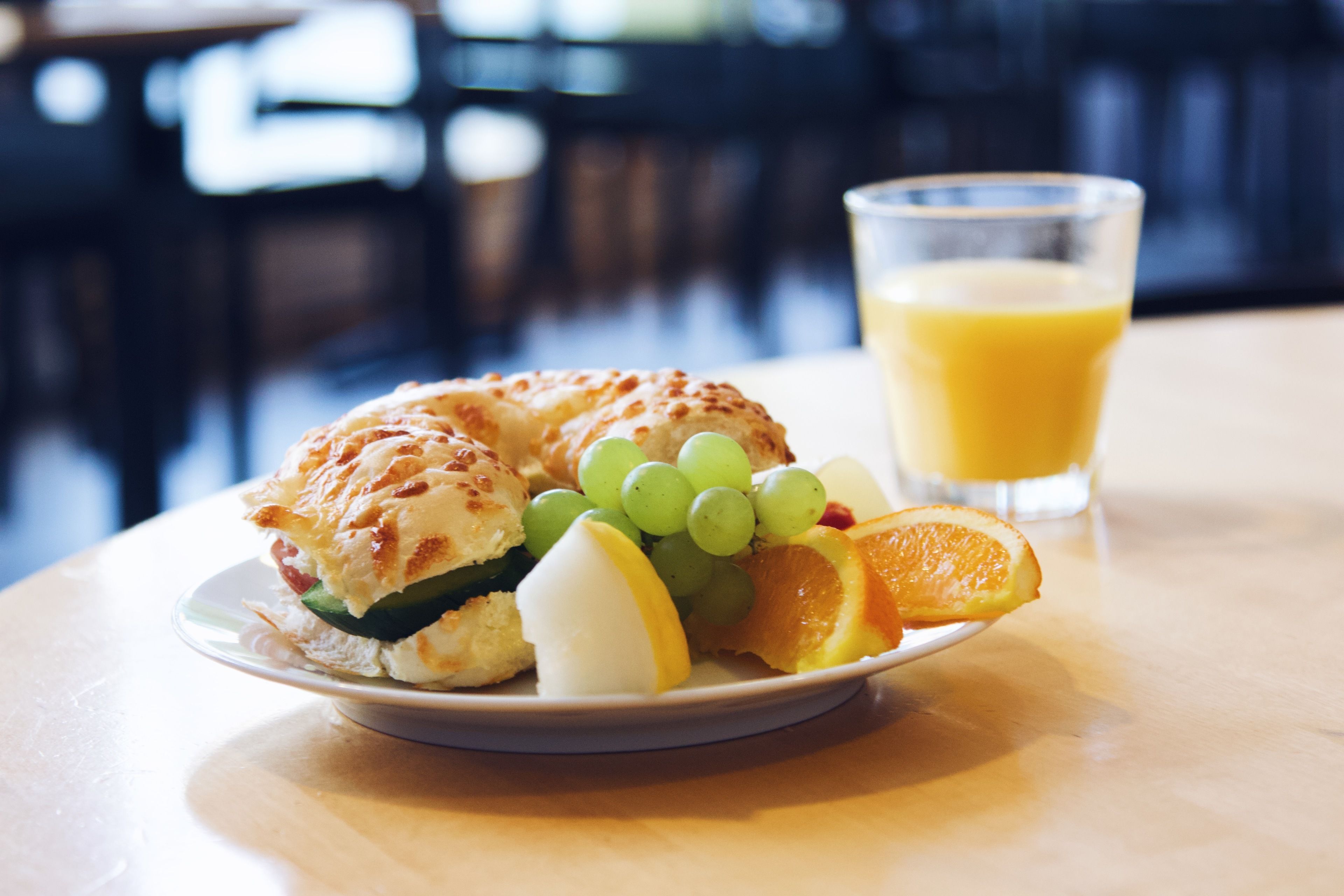 Une assiette contenant un croissant, des raisins, une tranche d’orange et un verre de jus d’orange, le tout posé sur une table.