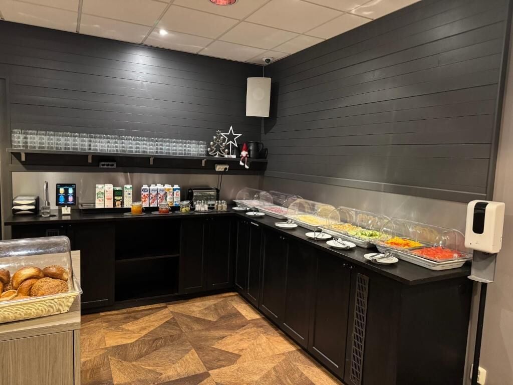 Zona de bufé con diversas opciones de comida, una estación de café y un dispensador de bebidas autoservicio.