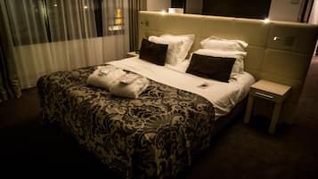Una habitación de hotel con una cama grande, una mesita de noche y un cabecero con iluminación integrada.