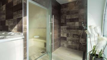 A modern bathroom with a glass shower enclosure, a white sink, and patterned tiles.