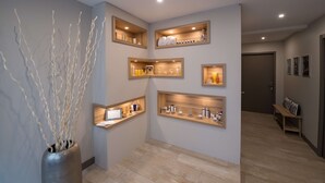 Un couloir doté d’étagères intégrées où sont exposés des articles de toilette et un vase décoratif orné de branches.