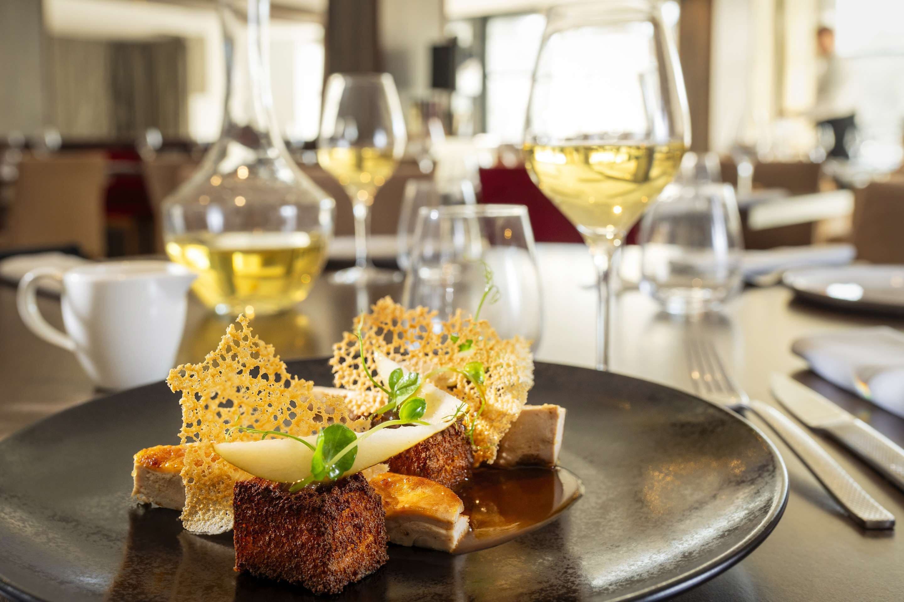 A dining table with a plate of food, wine glasses, and cutlery.